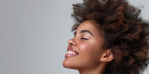 Banner portrait of serene girl with eyes closed and smile isolated on gray studio backdrop. Happy attractive sensual young woman with afro hairstyle, perfect skin, day makeup. Delight, enjoyment. Grey