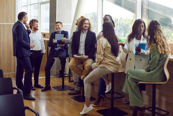 Group of diverse people men and women waiting for business conference talking in meeting room. Company employees working in modern office and discussing job and work projects. Team work concept.