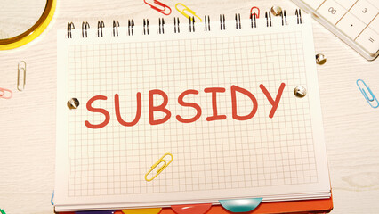 Business and finance concept. SUBSIDY the word in a notebook on the desk of a businessman, manager