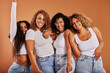 © Flamingo Images - Laughing women in jeans and white tops posing against an orange background