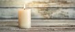 © Starkreal - Single white candle on a plain wooden surface