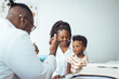 © Dragana Gordic - Smiling male doctor listen consult cute african boy make notes in patient card at medical checkup appointment, black mother and child son visit pediatrician talk in clinic, children healthcare concept