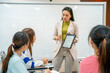 © mnirat - A woman is standing in front of a white board and holding a tablet