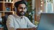 © Akmalism - Young Indian man sit at desk wear wireless headphones greets teacher start video call lesson to gain new knowledge, learn language, studying online, using laptop and modern videoconference application