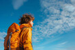 © xadartstudio - Young Explorer with Orange Backpack Gazing into the Blue Sky