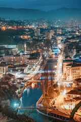 Wall Mural - As evening descends, the city's skyline glows with a warm hue, painting a mesmerizing picture against the backdrop of the Miljacka River.