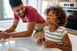 © NDABCREATIVITY - Happy african american family preparing healthy food in kitchen, having fun together on weekend