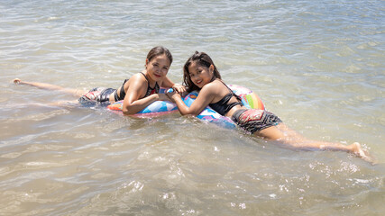 Two Philippine girls at San Remeigo Beach with inflatable unicorn innertubes