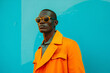 © Riverland Studio - a black man wearing sunglasses and orange coat standing in front of a colorful wall background