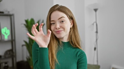 Sticker - Cheerful young blonde woman backstage, hilariously mimics a wild cat in a sexy yet funny claw gesture, wearing sweater indoors at home