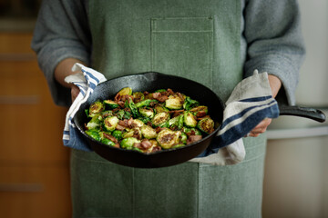 Wall Mural - Chef in a green apron holding a skillet with chopped brussel sprouts