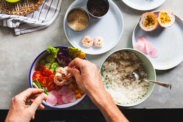 Wall Mural - Poke bowl with shrimp prepared by the chef containing white rice, mango, avocado, tomato, etc.