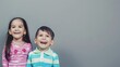 © Felippe Lopes - Happy children smiling and laughing against a grey background, embodying joy and innocence in colorful striped shirts.