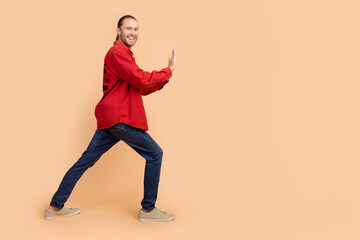 Sticker - Full size profile photo of nice young man arms push empty space wear red shirt isolated on beige color background