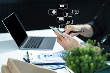 Wall Mural - Social media icons screen of businessman with smartphone and laptop computer at office at morning light.