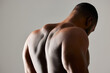 © peopleimages.com - Back, closeup and man in studio with body health, strong for fitness and exercise in gym. Bodybuilder, sports and gray background with muscle of model for training, zoom for anatomy or growth
