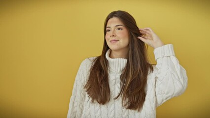 Canvas Print - Confident young hispanic woman, laughing with a natural smile, looks away off-side. beautifully wearing a sweater, isolated over yellow background