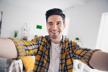 Canvas Print - Photo of handsome flirty guy dressed plaid shirt recording video winking eye indoors room home house