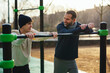 © BONNINSTUDIO/Stocksy - Son resting after training with his father on sports ground