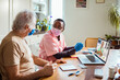 © Marko Geber - Nurse assisting elderly man with virtual doctor consultation at home