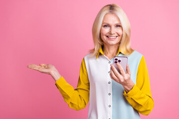 Wall Mural - Photo of nice aged lady hold phone empty space wear shirt isolated on pink color background