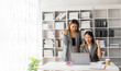© ArLawKa - Two young Asian businesswomen work on laptop computers in the office with reports. Colleagues discuss financial data in document analysis of new marketing projects.