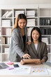 © ArLawKa - Two young Asian businesswomen work on laptop computers in the office with reports. Colleagues discuss financial data in document analysis of new marketing projects.
