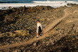 © Adrian Rodd/Stocksy - A man walks along the seashore looking for a good place to surf