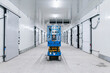 © Daniel Gonzalez/Stocksy - Scissors lift standing in hallway of warehouse