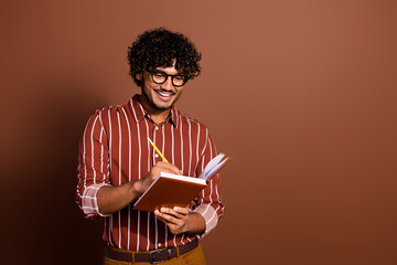 Canvas Print - Photo of nice young man rwrite notepad empty space wear striped shirt isolated on brown color background