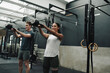 © Nicola Suttle/Stocksy - Positive athletes exercising with kettlebell in modern gym