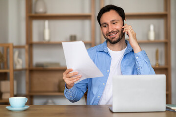 Aufkleber - A man is sitting at desk while talking on the phone, holding a piece of paper in his hand. He appears focused as he communicates using the phone and glances at the paper intermittently.