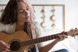 © Jordana Sheara/Stocksy - Beautiful woman with multicolored hair playing guitar at home