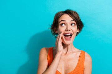 Wall Mural - Portrait of optimistic funky girl with short hairdo wear orange knit top tell secret look empty space isolated on blue color background