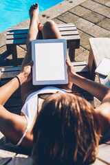 Wall Mural - Top view of young woman resting on sunbed and enjoying summer vacation in resort spa while installing application on modern tablet with blank copy space screen for your advertising information content