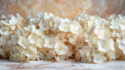   A group of white flowers resting atop a wooden table beside a vase adorned with white blooms