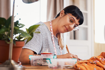 Notes, woman and writing with fashion designer in home studio for style with measuring tape for profession. Tailoring, couture and material or fabric for handmade clothing for business in Sweden.