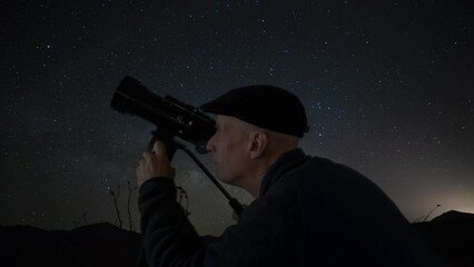 Wall Mural - an amateur astronomer looking at stars through a telescope
