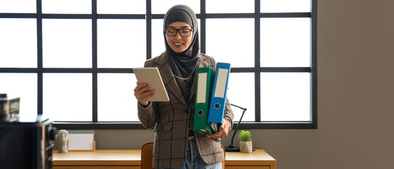 Poster - Young Muslim businesswoman with document folders in office