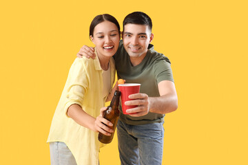 Wall Mural - Young couple with beer on yellow background