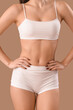 © Pixel-Shot - Young woman in white underwear on brown background