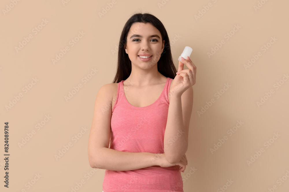 Happy smiling young woman with crystal deodorant on beige background