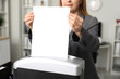 © Pixel-Shot - Adult secretary destroying paper sheet using shredder in office, closeup
