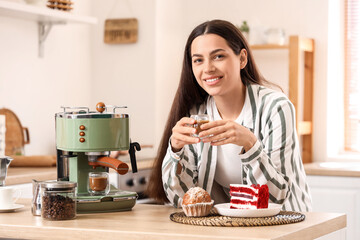 Wall Mural - Beautiful young happy woman with modern coffee machine and desserts in kitchen