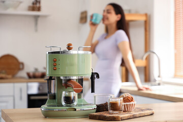 Poster - Beautiful young woman with cups of coffee and modern machine in kitchen