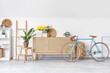 © Pixel-Shot - Interior of living room with bicycle and yellow narcissus flowers on wooden cabinet