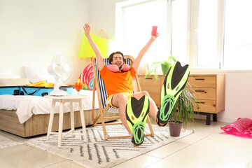 Wall Mural - Male tourist with flippers and cup resting in deck chair at home on vacation