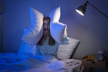 Canvas Print - Stressed young woman with pillows suffering from insomnia in bedroom at night