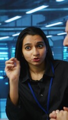 Poster - vertical video programmers talking in high tech server hub, using pcs to analyze data. colleagues ex