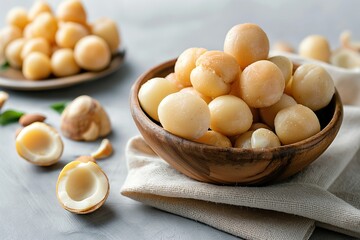 Raw peeled macadamia nuts in wooden bowl on rustic wooden background
